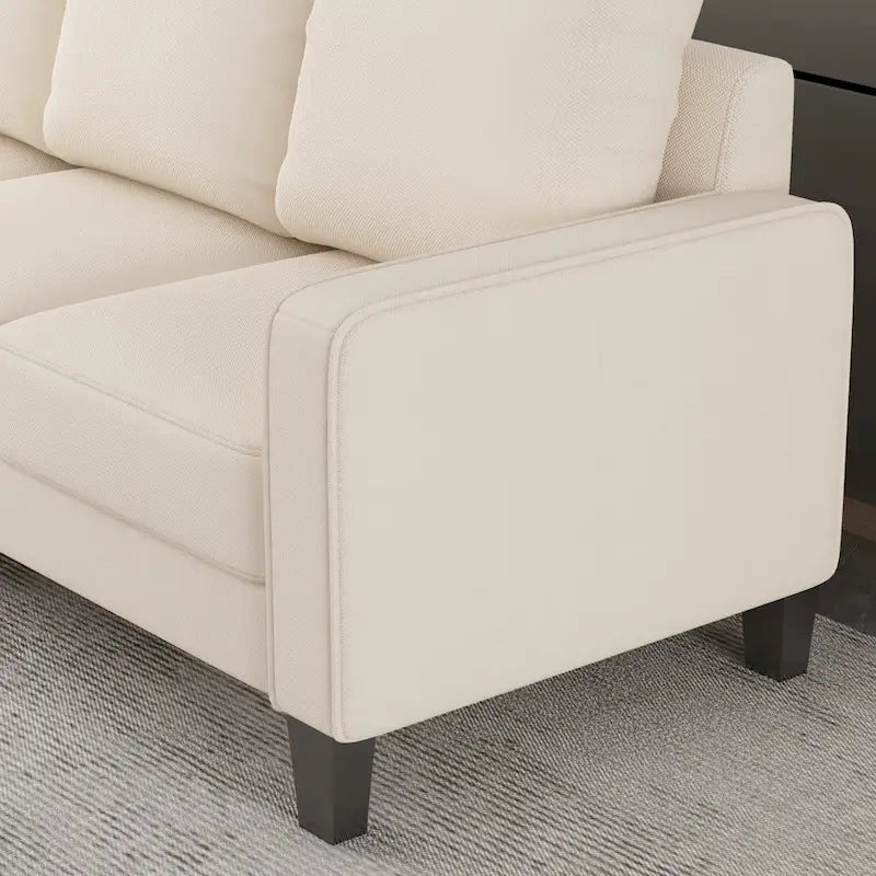 Beige stoffen bank met rechte armleuningen en gecapitonneerde rugleuning